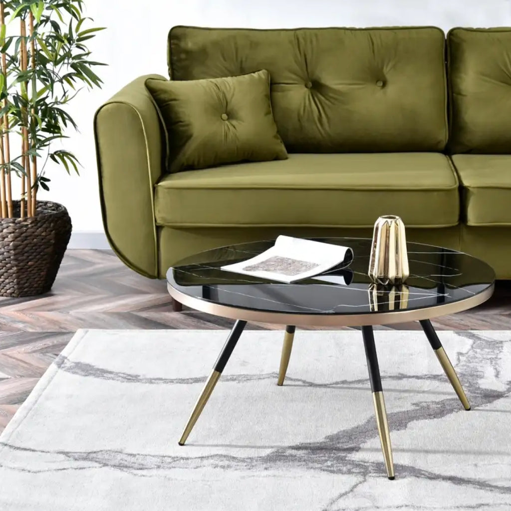 A sleek Estella black coffee table with gold legs and a black marble top.