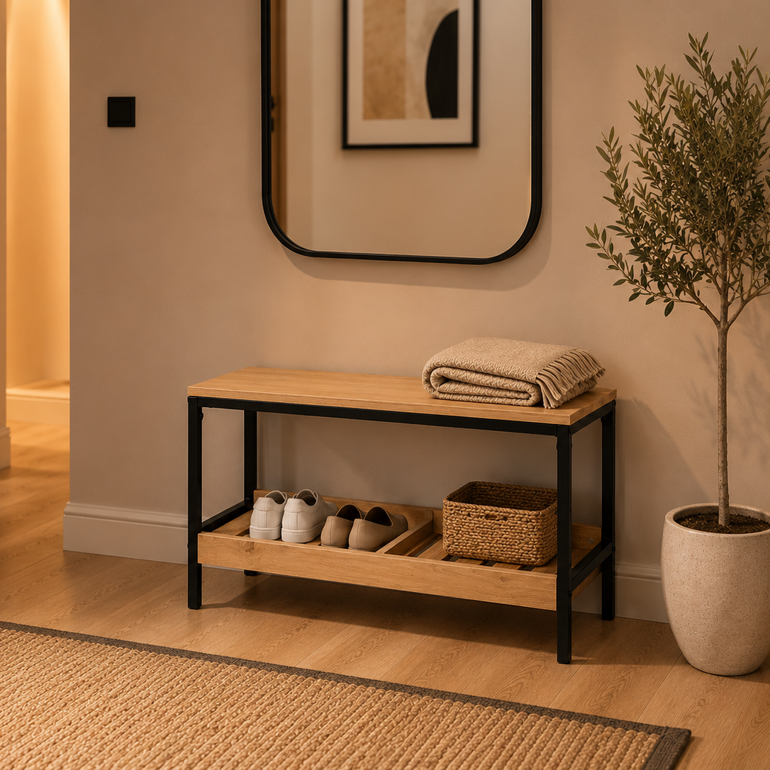 A modern entryway shoe bench with a light wood top and black metal frame, styled in a warm-toned hallway with a folded blanket, shoes, basket, mirror, and potted plant.