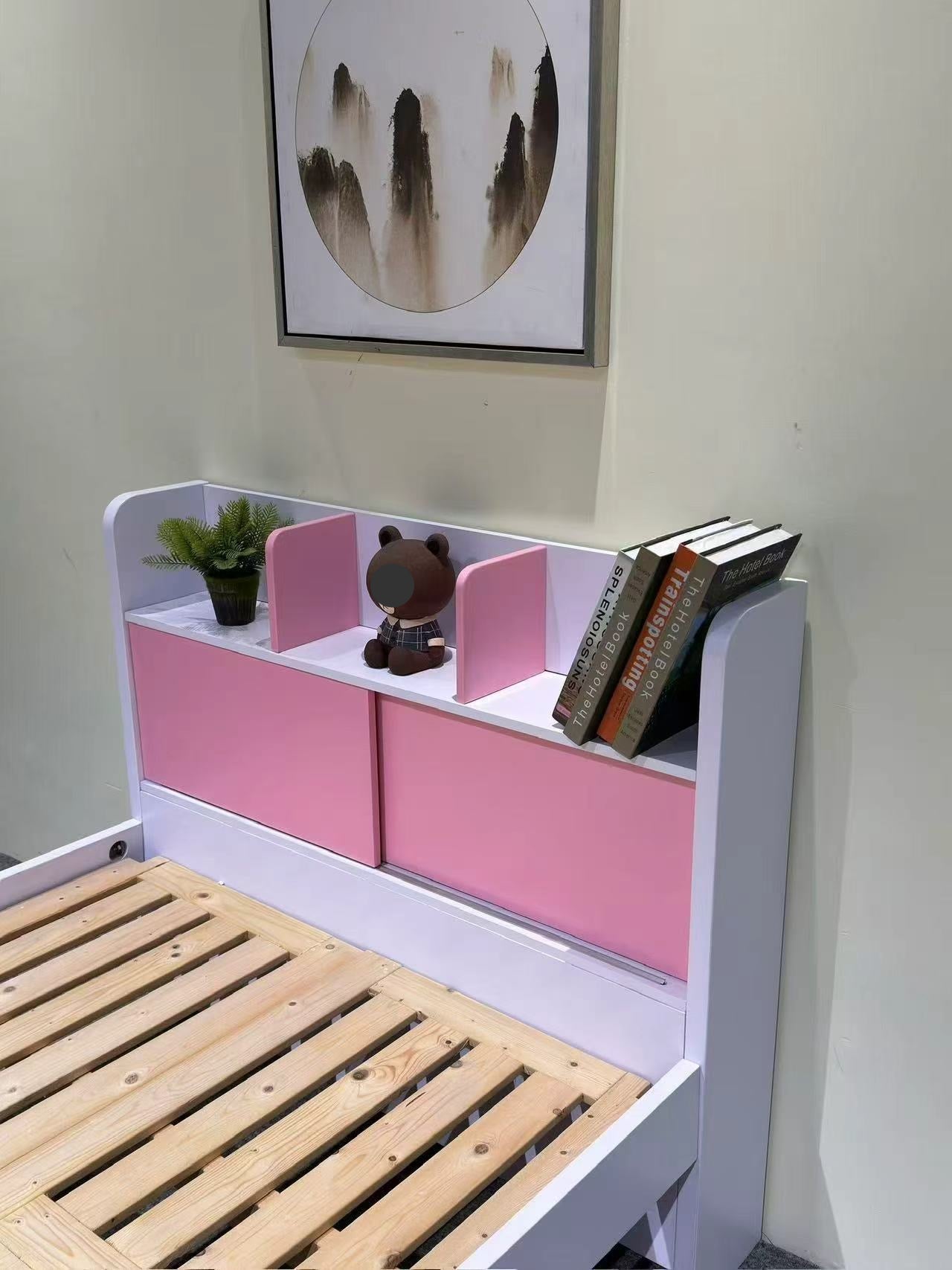 Children's bed with pink storage drawers and books on a white wall background
