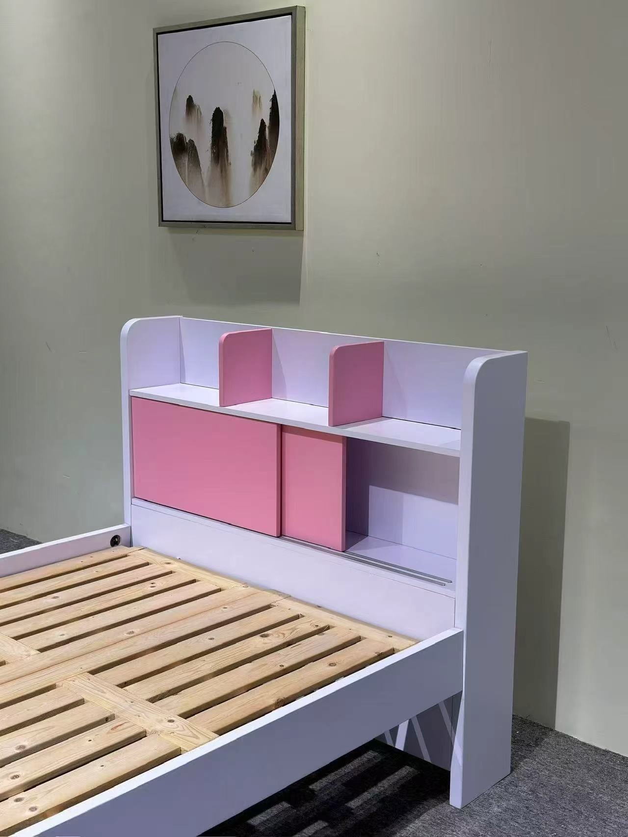 Children's bed with pink storage compartments and wooden slats, framed picture on wall.