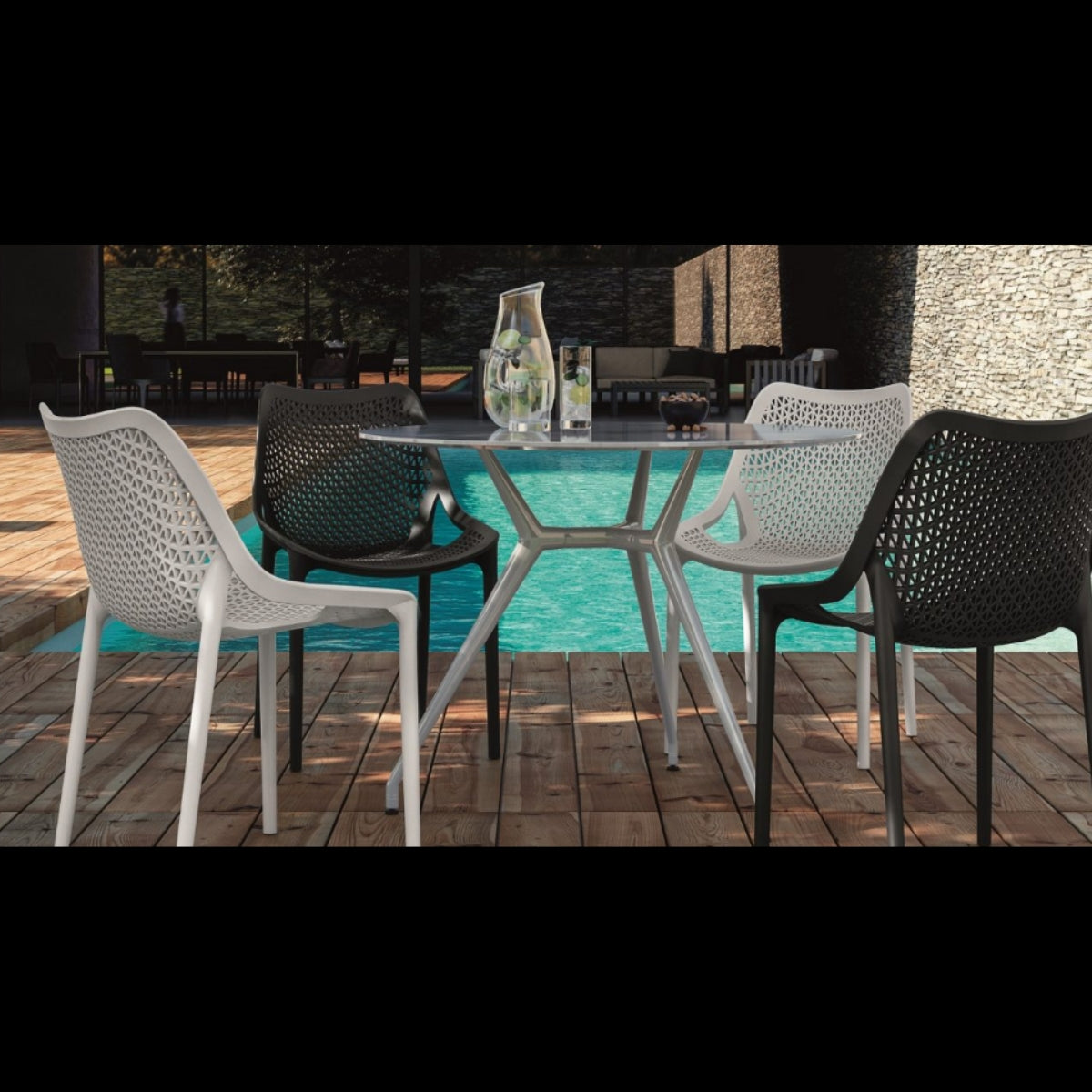 Replica Bilros Chairs in black, white, and dark grey around a table by a swimming pool, showcasing their outdoor use