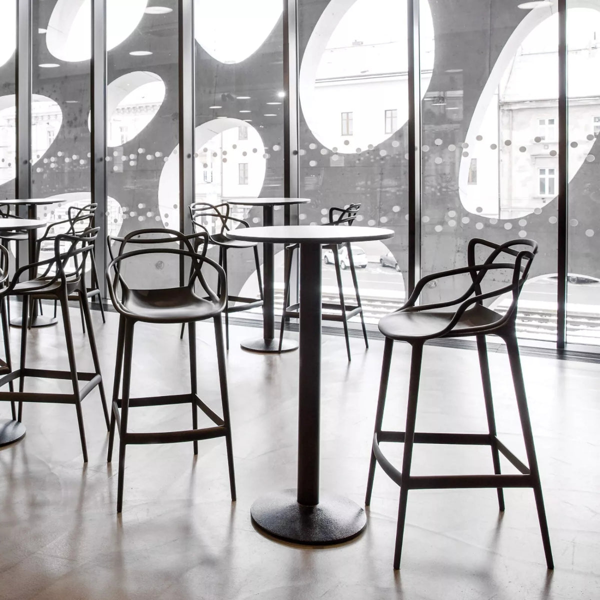 Modern bar stools and tables in a stylish interior setting with large windows.