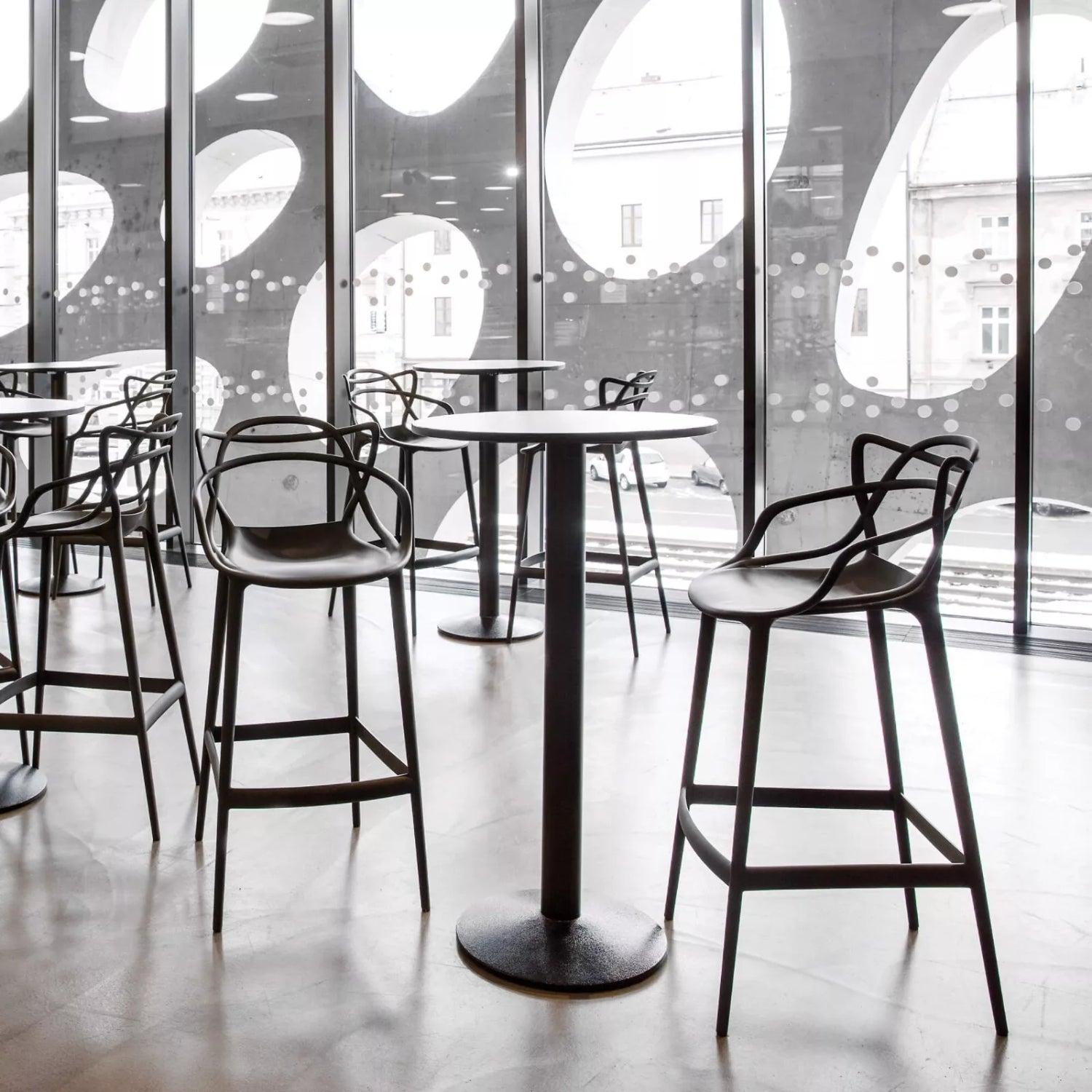 Modern bar stools and tables in a stylish interior setting with large windows.