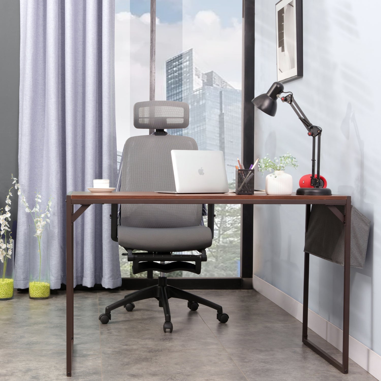 A desk with a laptop and grey Kyona ergonomic chair in front of a window.