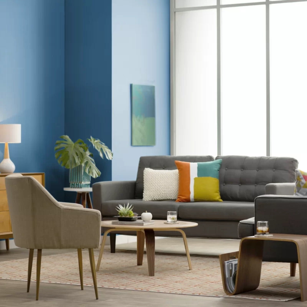 A living room with blue walls and furniture, including a REPLICA EAMES MOLDED PLYWOOD COFFEE TABLE.