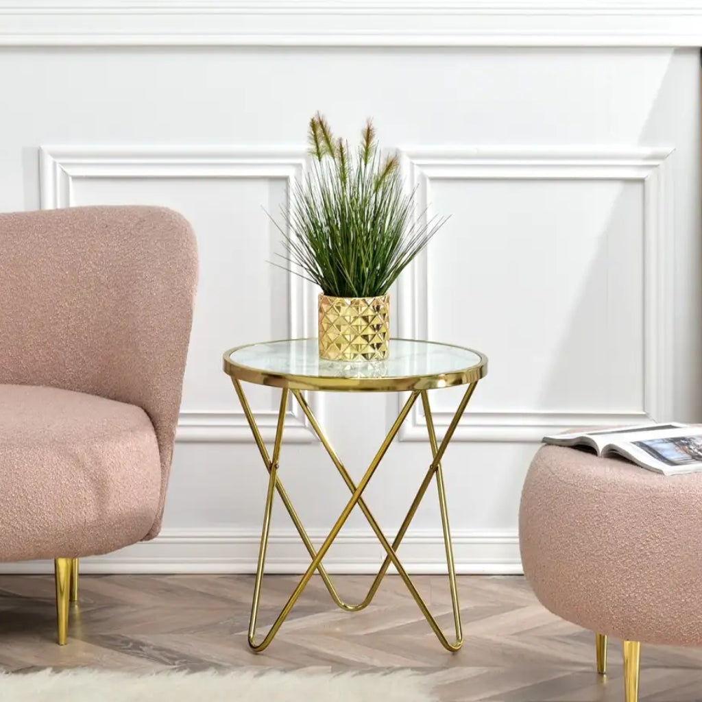 A pink chair and ottoman with a gold frame, placed next to an Aden White top and Gold End Table.