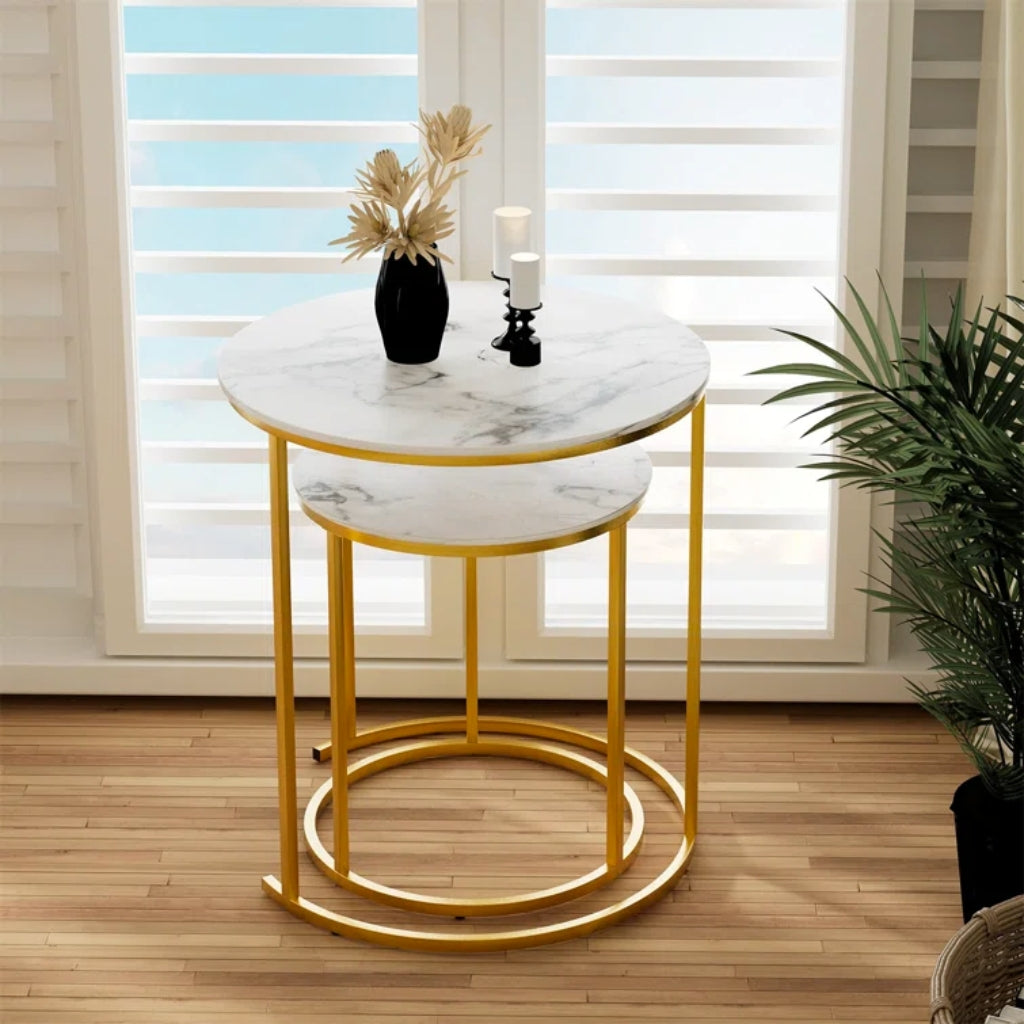 A stylish Dalia Nesting End Table Set Gold with a round marble top, gold legs, and a plant.