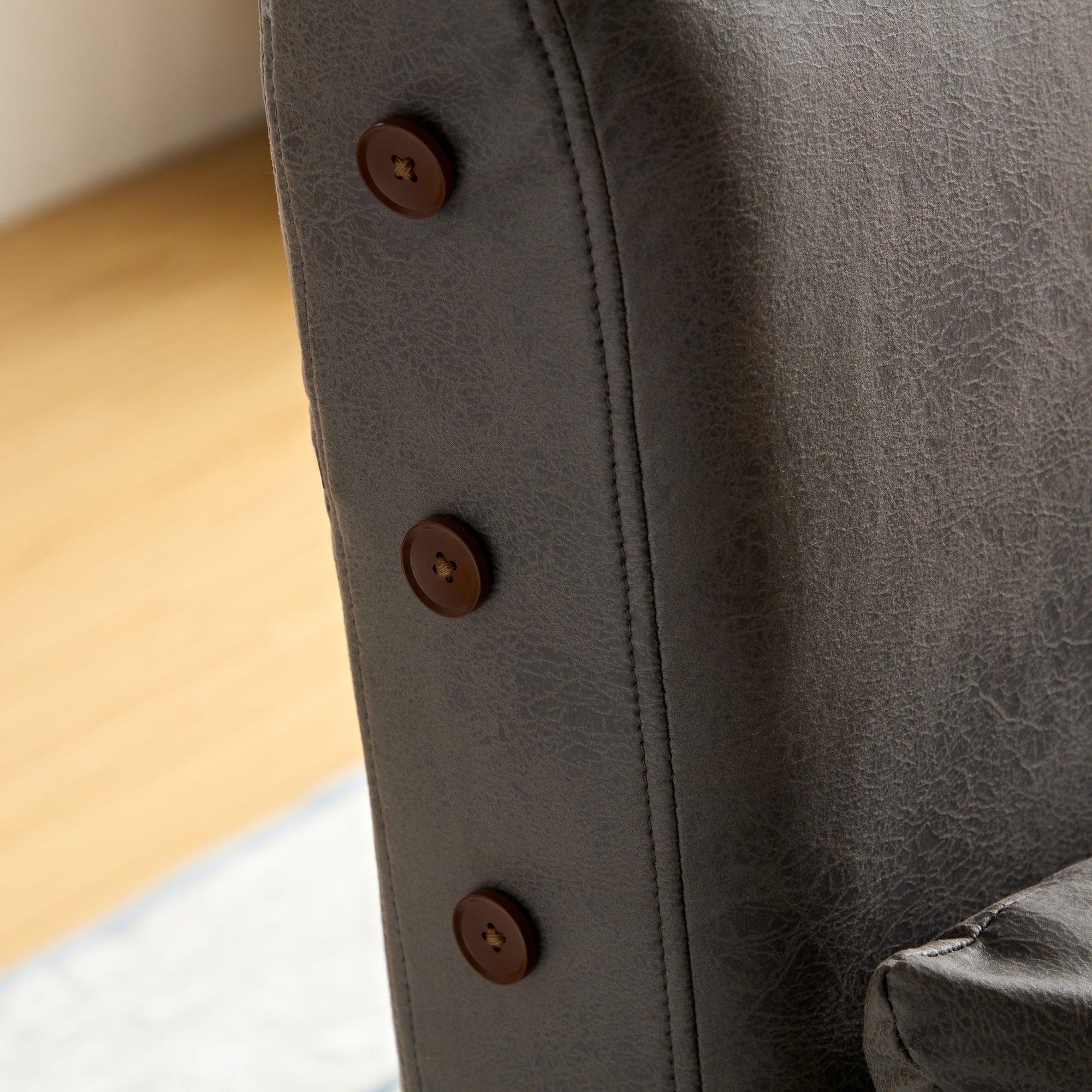 Close-up of a gray leather chair with buttons, part of the Ariton Tri-Fold Sleeper Convertible Chair with Pillow range.