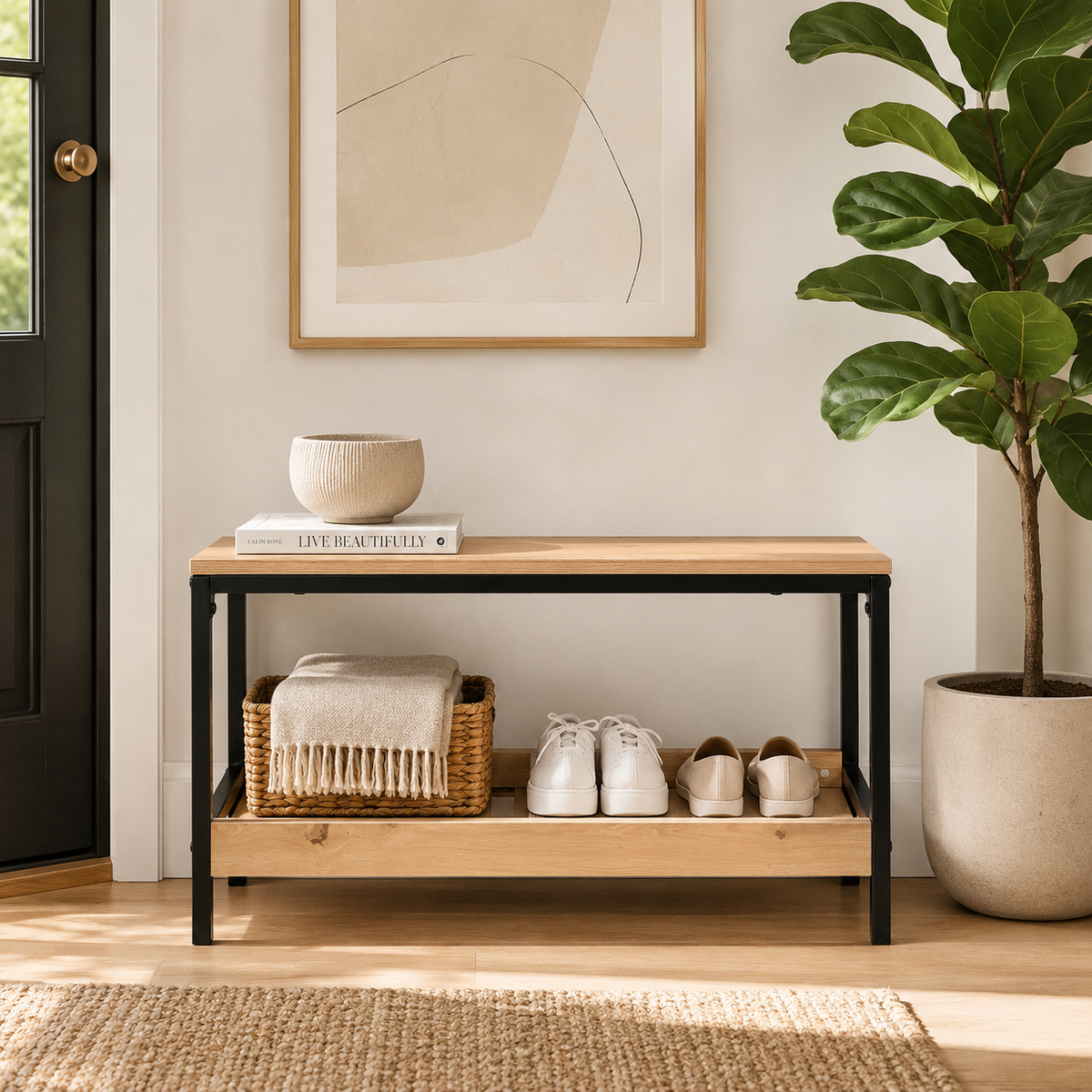 A light wood and black metal entryway console table styled in a bright, modern room. The table is decorated with a small ceramic bowl, a book, a woven basket with a throw blanket, and a pair of white sneakers.