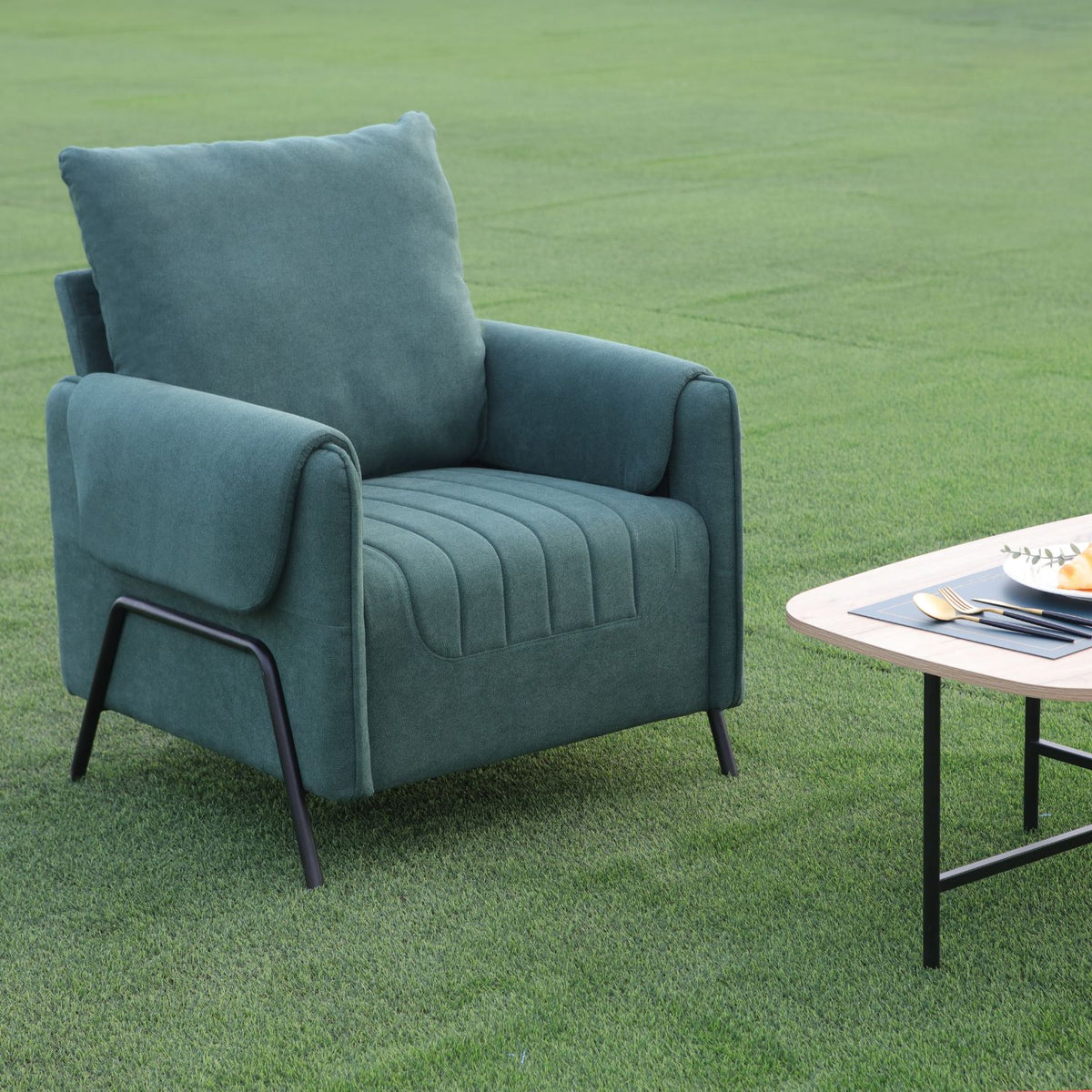 Kreslo Green Armchair in an outdoor setting next to a small table.
