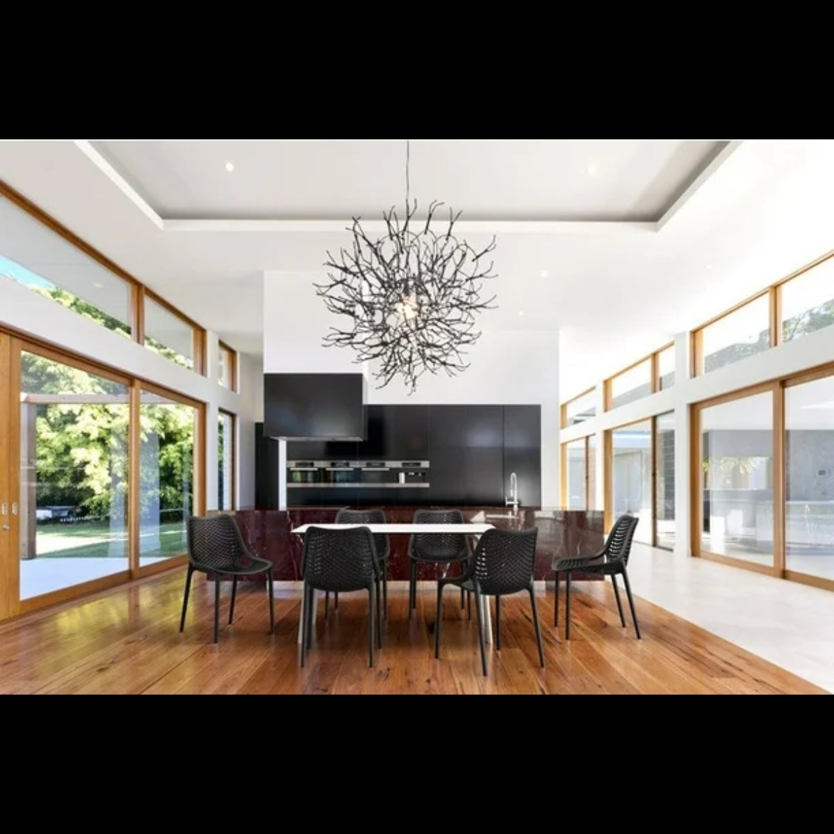 Black Replica Bilros Chairs around a dining table in a modern, open-plan indoor space