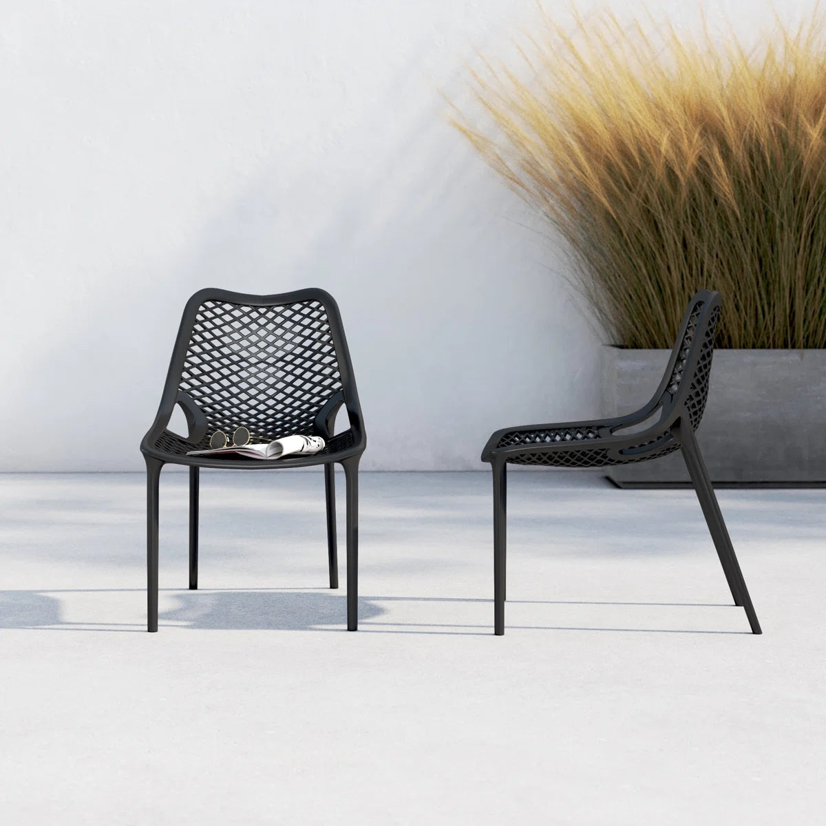 Two black Replica Bilros Chairs on a patio, suitable for indoor and outdoor use