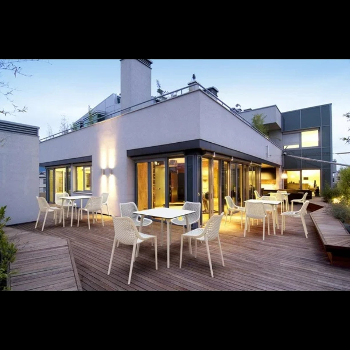White Replica Bilros Chairs around a dining table on a sunny outdoor patio, highlighting their use as an outdoor dining set